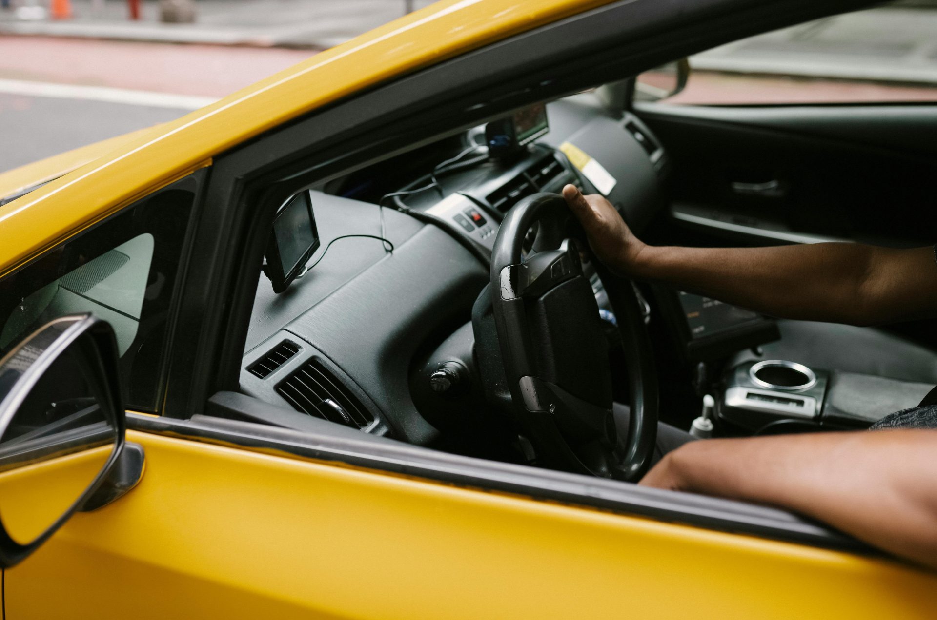 Von oben: Anonymer männlicher Fahrer (ethnische Herkunft) fährt Taxi mit einem Gerät, das Informationen entlang der Route liefert.